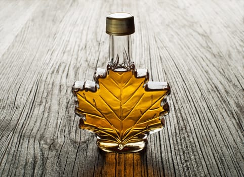 Maple syrup in glass bottle on wooden table