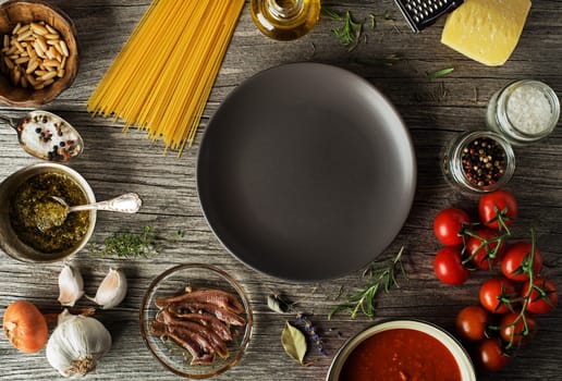Spaghetti with ingredients for cooking pasta on wooden background