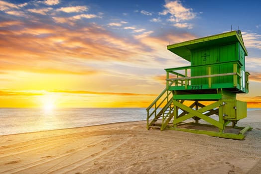 Miami South Beach sunrise with lifeguard tower and coastline with colorful cloud and blue sky.