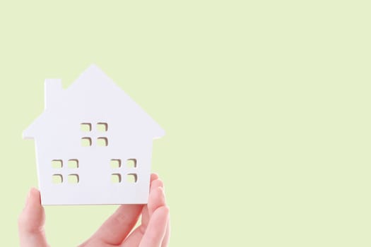 Hand holding miniature model of house on white background