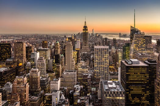 New York City. Manhattan downtown skyline with illuminated Empire State Building and skyscrapers at dusk.