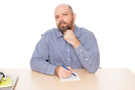 A thoughtful man with a beard at his desk against a white background