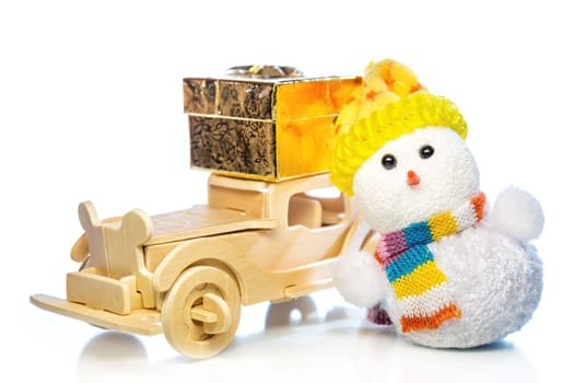 Christmas snowman toy and old vintage wooden automobile with golden or yellow gift box on white background. Main focus of image on Santa Claus and selective on wood car