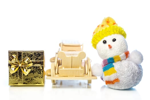 Christmas snowman toy and old vintage wooden automobile with golden or yellow gift box on white background. Main focus of image on Santa Claus and selective on wood car
