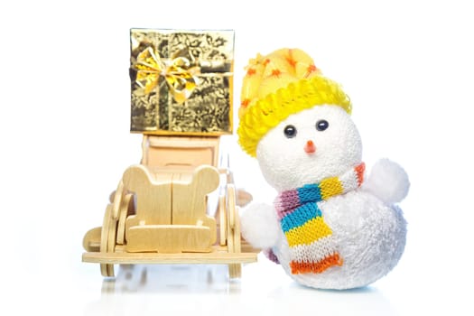 Christmas snowman toy and old vintage wooden automobile with golden or yellow gift box on white background. Main focus of image on Santa Claus and selective on wood car