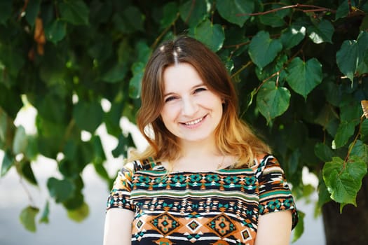 Happy smiling woman on green foliage background. Shallow depth of field. Selective focus.
