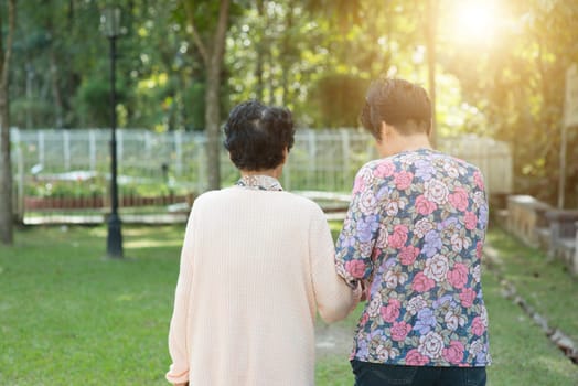 Candid shot of rear view Asian senior adult women walking at outdoor park in the morning.