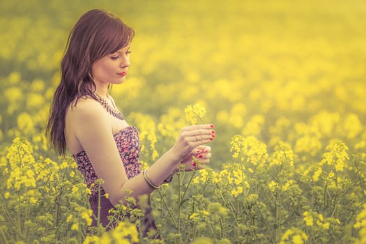 Attractive happy young girl enjoying the warm summer sun and her health in a wide green and yellow meadow. Part of series.