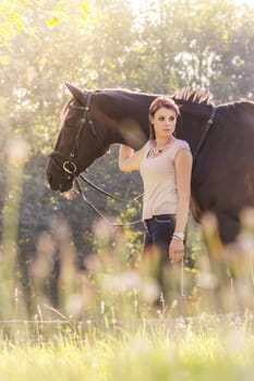 Scene of a teenager horsewoman holding her best animal friend in a lovely sunny outdoor scene. Portrait format with copyspace.