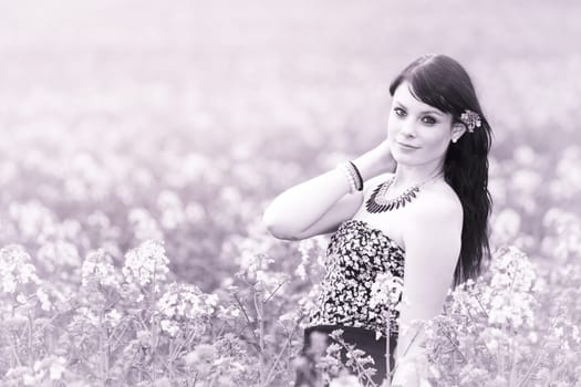 Attractive happy young girl enjoying the warm summer sun and her health in a wide green and yellow meadow. Part of series.