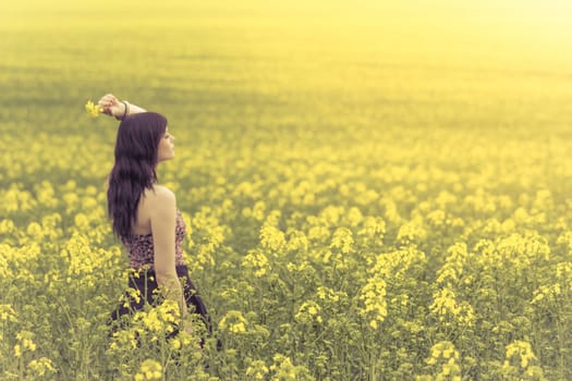 Attractive genuine young girl enjoying the warm summer sun in a wide green and yellow meadow. Part of series.