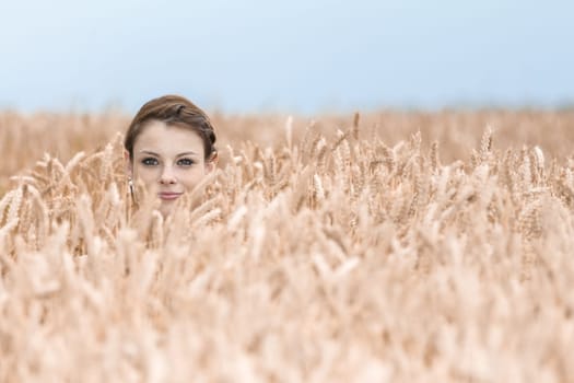 Beautiful girl playing hide and seek in nature. Special perspective. Copy space.