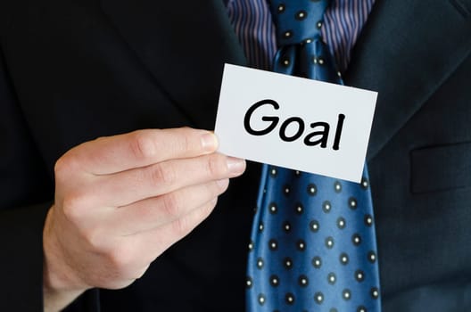 Goal text note concept over business man background.