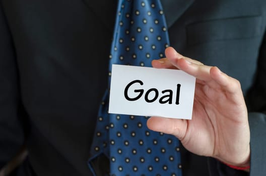Goal text note concept over business man background.