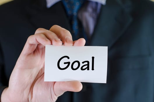 Goal text note concept over business man background.
