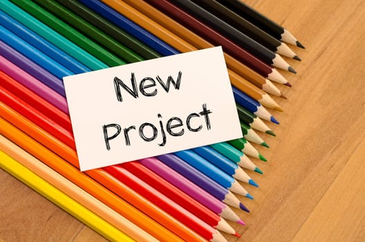 Blank white paper and colored pencil on wooden background