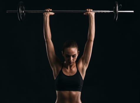 Shot of a beautiful young woman in a workout gear lifting weights