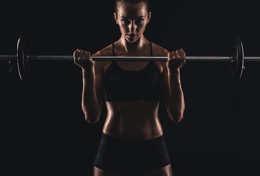 Shot of a beautiful young woman in a workout gear lifting weights