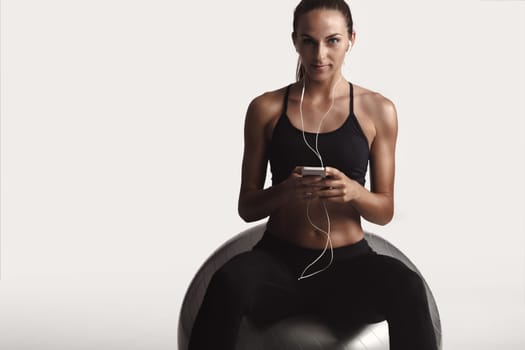 Shot of a beautiful young woman setting the music playlist for the workout.