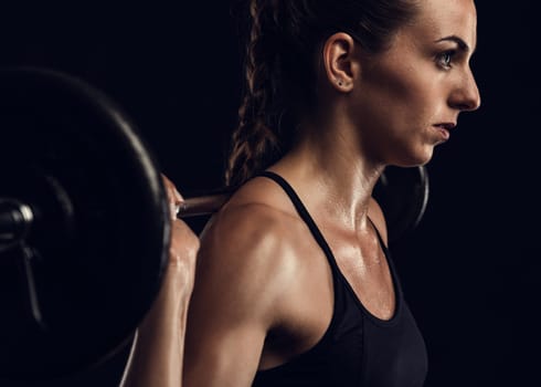Shot of a beautiful young woman in a workout gear lifting weights