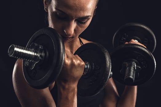 Shot of a beautiful young woman in a workout gear lifting weights