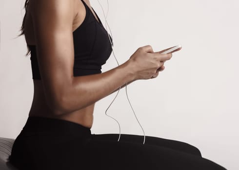 Shot of a beautiful young woman setting the music playlist for the workout.