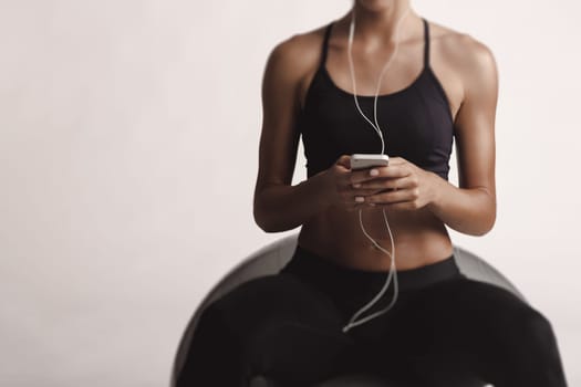 Shot of a beautiful young woman setting the music playlist for the workout.