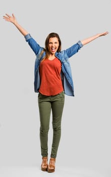 Beautiful happy woman with arms up over a gray background