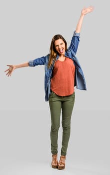 Beautiful happy woman with arms up over a gray background