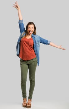 Beautiful happy woman with arms up over a gray background