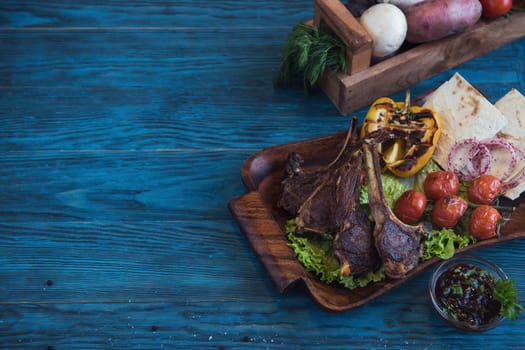 Grilled lamb meat with vegetable on a blue wooden background