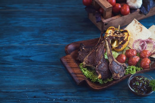 Grilled lamb meat with vegetable on a blue wooden background