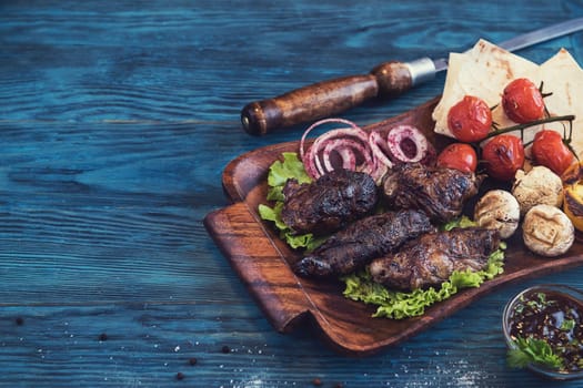 Grilled lamb meat with vegetable on a blue wooden background