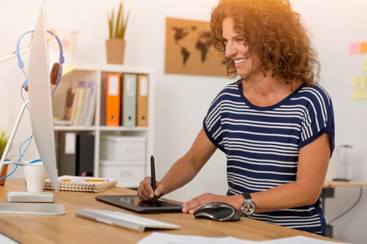 Middle age designer working on a desktop with a stylus pen