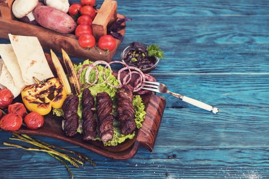 Grilled lamb meat with vegetable on a blue wooden background