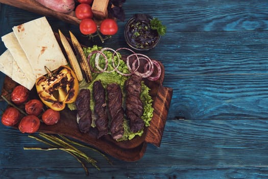 Grilled lamb meat with vegetable on a blue wooden background