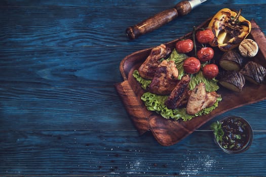 Grilled chicken meat with vegetable on a blue wooden background