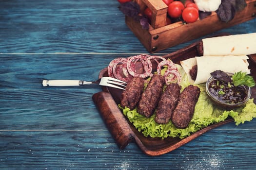 Grilled lula kebab - meat dish, with vegetable on a blue wooden background