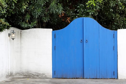 Old wooden blue gateway with white wall