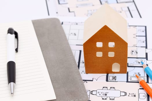 Miniature model of house on blueprints, construction plan