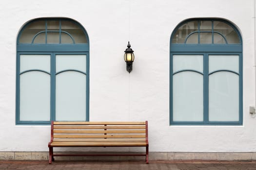 outdoor bench with white wall on brick street