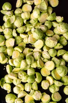 green fresh whole and cut organic Brussels sprouts, isolated on black glossy background