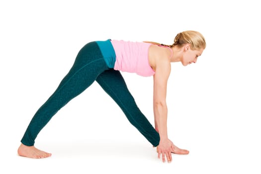 Lateral full-body view of a young woman against a white background showing a variation of the yoga exercise triangle (Triconasana).
