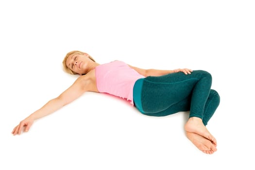 Lateral full-body view of a young woman lying on the floor in the yoga position "Crocodile"" (Nakrasana) on a white background with arms stretched out to the side."