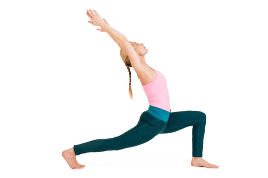 Side full-body view of a young woman during yoga exercise "the warrior 1"" (Virabhadrasana 1) against a white background with a slight shadow"