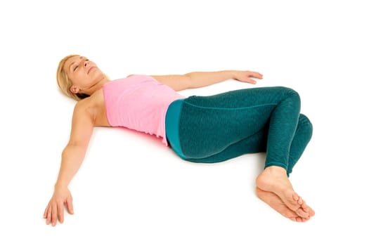 Lateral full-body view of a young woman lying on the floor in the yoga position "Crocodile"" (Nakrasana) on a white background with arms stretched out to the side."