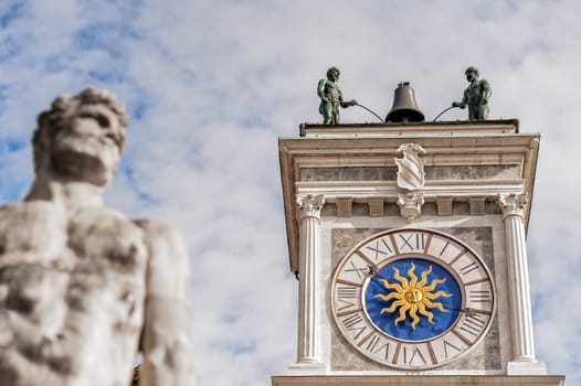 Clock tower with bell. Blurred in foreground the Hercules Statue.