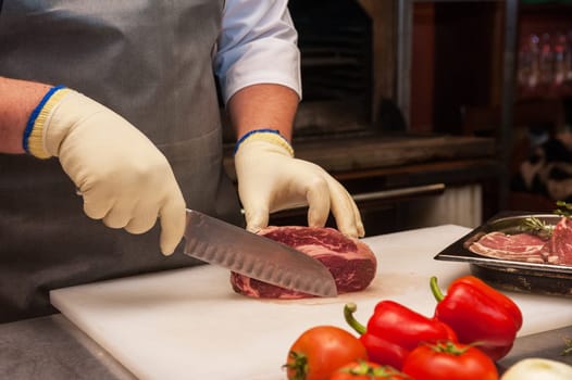 Chef cutting meat on steaks with knife