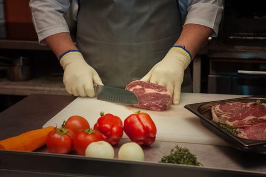 Chef cutting meat on steaks with knife