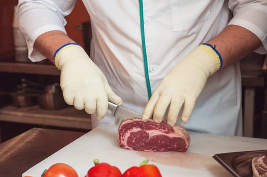 Chef cutting meat on steaks with knife